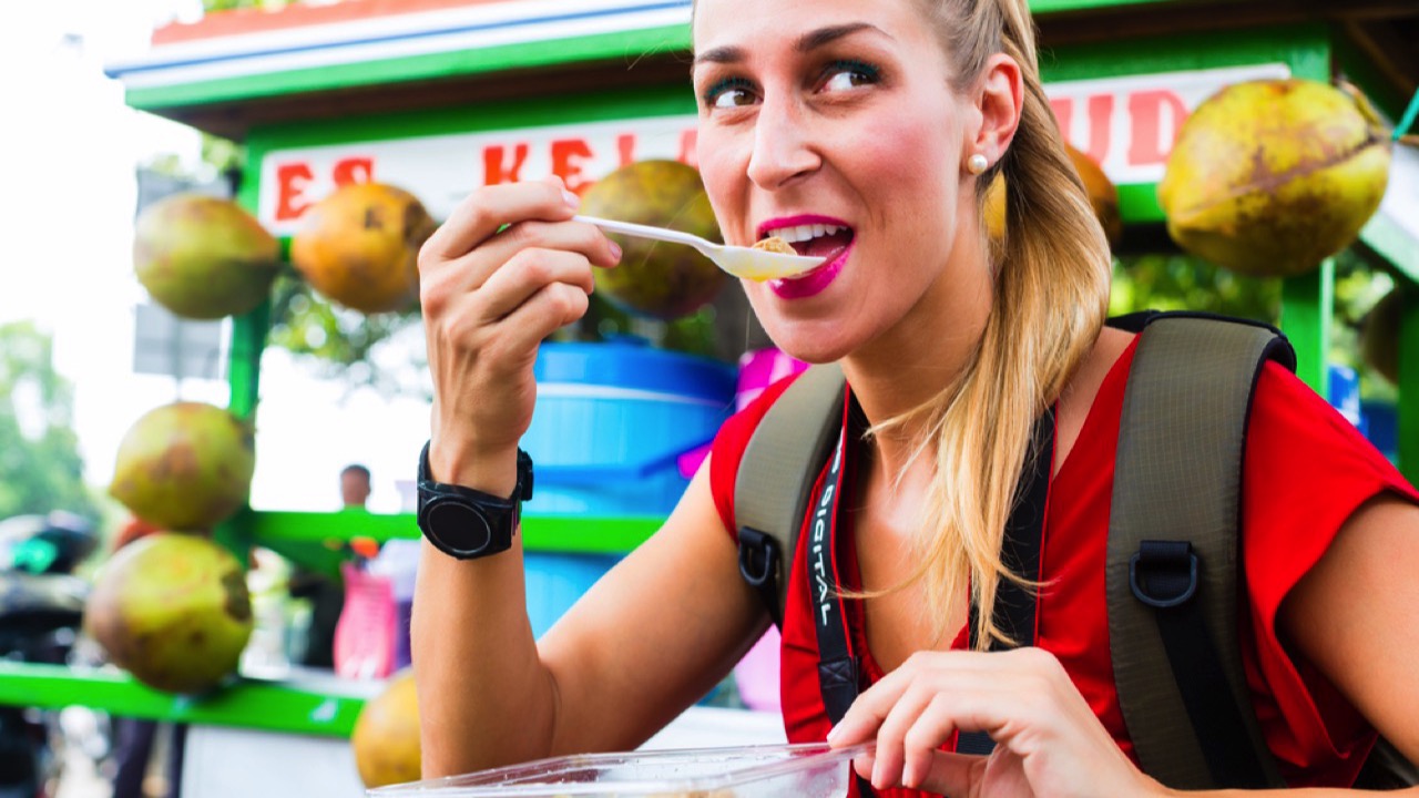 European woman eating street food in Indonesia