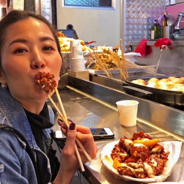 Young woman traveler eating street food in South Korea